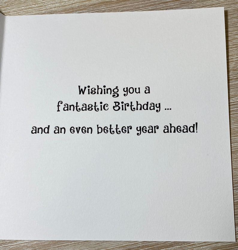 Pu&ograve; includere: Un biglietto bianco con testo nero che dice "Wishing you a fantastic Birthday... and an even better year ahead!"