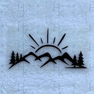 Könnte beinhalten: Schwarz-weiße Silhouette einer Sonne, die über Bergen mit Bäumen im Vordergrund aufgeht.
