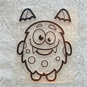 Könnte beinhalten: Eine schwarze Umrisszeichnung eines Cartoon-Monsters mit einem lächelnden Gesicht, zwei kleinen Flügeln und drei Kreisen auf seinem Körper. Das Monster hat große Augen und einen gezackten Mund. Das Bild befindet sich auf einem weißen, strukturierten Hintergrund.