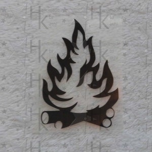 Könnte beinhalten: Schwarzer Metallausschnitt eines stilisierten Lagerfeuers mit Flammen und Holzscheiten.