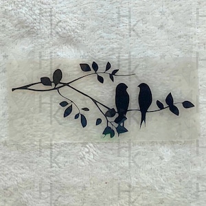 Könnte beinhalten: Silhouette von zwei Vögeln, die auf einem Ast mit Blättern sitzen. Die Vögel schauen sich an und der Ast ist gebogen.