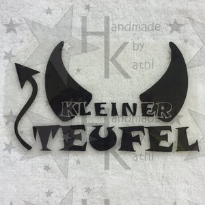 Könnte beinhalten: Schwarzer Vinyl-Aufkleber mit einem Teufels Schwanz und Hörnern und dem Text "KLEINER TEUFEL" in einer fetten, stilisierten Schrift.