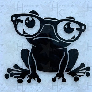 Könnte beinhalten: Schwarze Silhouette eines Frosches mit runden Brillen. Der Frosch sitzt mit gespreizten Beinen und weit aufgerissenen Augen.