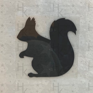 Könnte beinhalten: Schwarze Silhouette eines Eichhörnchens mit braunem Kopf und Schwanz. Das Eichhörnchen ist nach links gerichtet und hat seinen Schwanz hinter sich eingerollt.