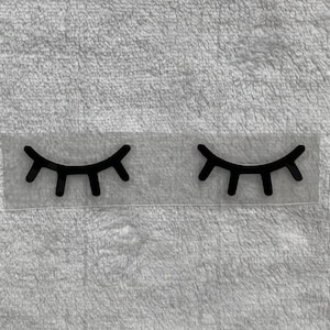 Könnte beinhalten: Zwei schwarze Wimpern auf einem transparenten Hintergrund. Die Wimpern sind geschlossen und haben ein einfaches Design.