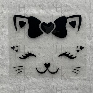 Könnte beinhalten: Schwarz-weißes Katzen Gesicht mit Schleife und Herzen. Die Katze hat Wimpern und eine kleine Herznase.