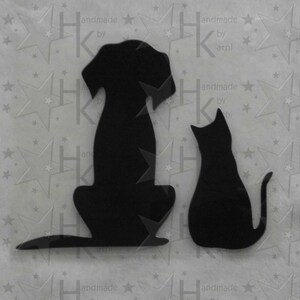 Könnte beinhalten: Schwarze Silhouette eines Hundes und einer Katze, die sich gegenübersitzen. Der Hund ist links und die Katze rechts. Das Bild ist auf einem weißen Hintergrund mit Sternen.
