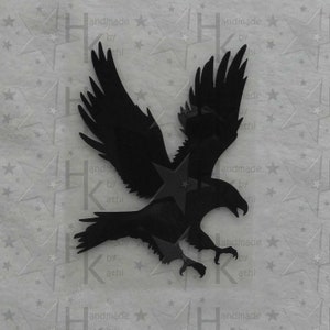 Könnte beinhalten: Schwarze Silhouette eines Habichts oder Adlers mit ausgebreiteten Flügeln, der nach unten fliegt. Die Silhouette ist aus einem festen Material, möglicherweise Metall, ausgeschnitten.