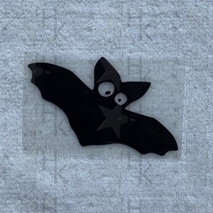 Könnte beinhalten: Schwarze Silhouette einer Fledermaus mit großen Augen auf einem transparenten Hintergrund.