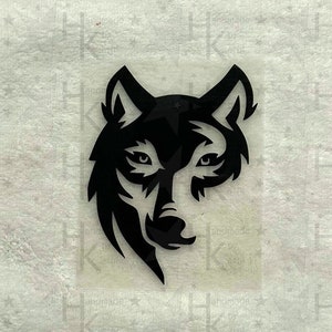 Könnte beinhalten: Schwarzes Wolfskopf-Design. Das Gesicht des Wolfes ist stilisiert und symmetrisch dargestellt, mit scharfen Linien und einem Fokus auf Augen und Schnauze. Das Design befindet sich auf transparentem Hintergrund.