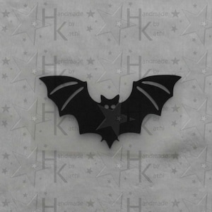 Könnte beinhalten: Schwarzer Filz-Fledermaus-Ausschnitt mit einer Sternform in der Mitte. Die Fledermaus befindet sich auf einem weißen Hintergrund mit einem sich wiederholenden Muster aus Sternen und dem Text "handmade by athi".