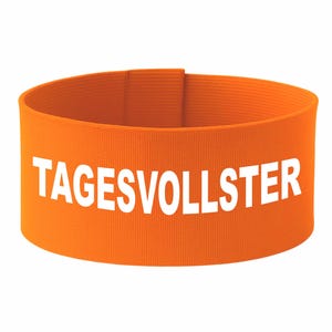 Könnte beinhalten: Ein orangefarbenes Stoffarmband mit dem weißen Text "TAGESVOLLSTER" auf der Vorderseite. Das Armband ist einfarbig und scheint aus einem gewebten Material zu bestehen. Der Text ist in einer fetten, serifenlosen Schriftart.