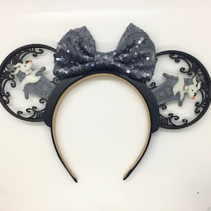 May include: Black and white mouse ears with a gray sequined bow and a 3D design of a ghost dog and a tombstone.