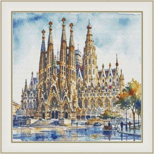 May include: A framed watercolor painting depicting the Sagrada Familia basilica with its tall, intricate spires and stone facade. The scene includes a blue sky, a street level with small figures, a bicycle, and a tree, all rendered in soft tones.