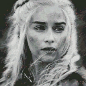 May include: A black and white portrait of a woman with long, flowing white hair. She has a serious expression on her face.