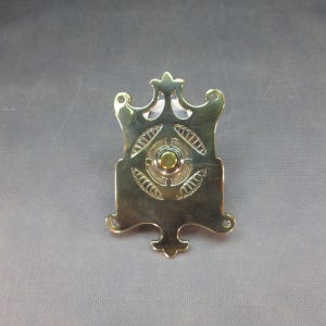 Puede incluir: Un timbre de puerta de latón con un diseño ornamentado y un botón redondo en el centro.