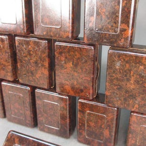 May include: A stack of ten small, rectangular boxes made of brown mottled plastic. The boxes are arranged in a pyramid shape.