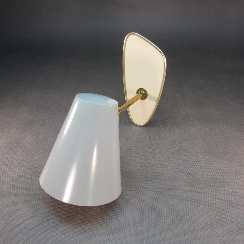Pu&ograve; includere: Uno specchio da toeletta vintage a parete con uno specchio ovale bianco e un paralume bianco a forma di cono.