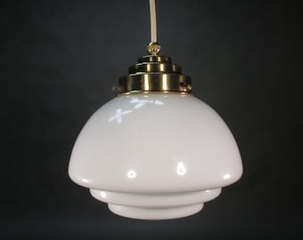 May include: A white glass pendant light with a brass fixture. The light has three tiers and a rounded shape.