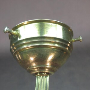May include: A gold-toned metal lamp socket with three screws. The socket is designed to hold a light bulb and has a threaded base.