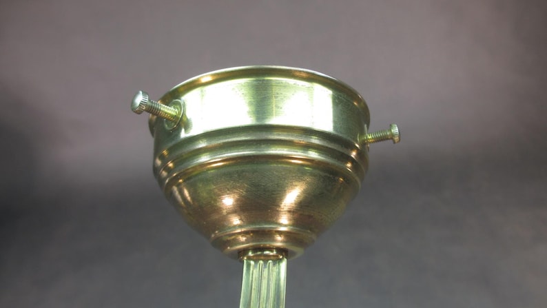 May include: A gold-toned metal lamp socket with three screws. The socket is designed to hold a light bulb and has a threaded base.