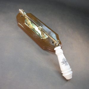 Könnte beinhalten: Ein brauner Toilettengriff aus Holz mit Messingbeschlägen und einem weißen Porzellangriff. Auf dem Porzellangriff steht das Wort "ZIEHE" in schwarzer Schrift. Der Griff ist auf einer braunen Holzplatte montiert.