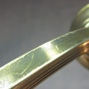 May include: A close-up of a brass door handle with a smooth, polished finish. The handle has a rounded shape and a long, slender arm.