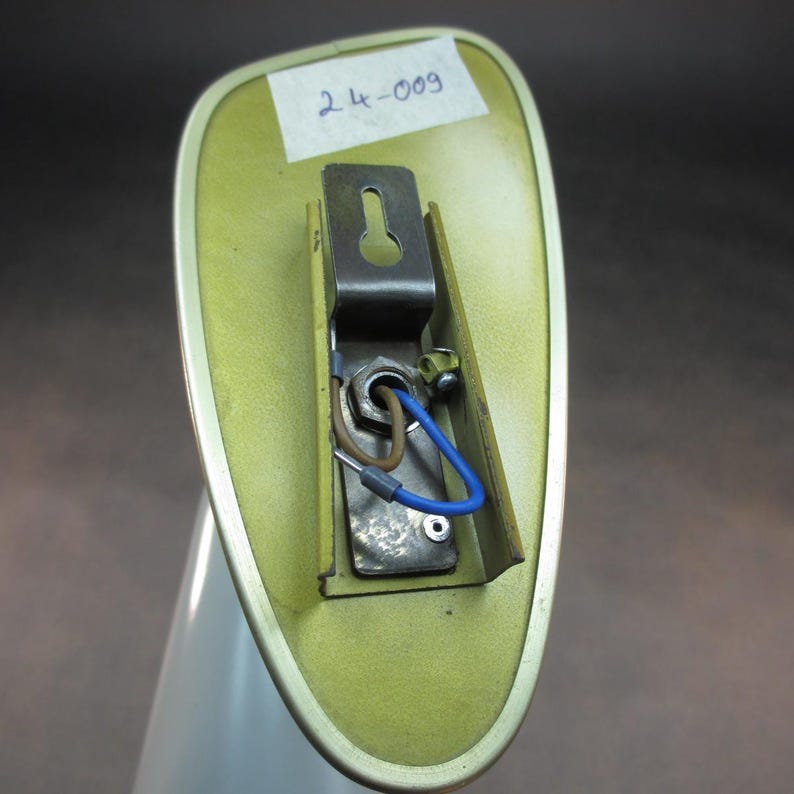 Pu&ograve; includere: Il retro di un pezzo di auto verde e argento con una staffa metallica e fili. Il pezzo &egrave; etichettato "24-009".