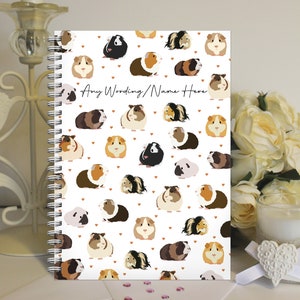 May include: A white spiral bound notebook with a pattern of colourful guinea pigs and brown hearts. The text "Any Wording/Name Here" is printed on the cover.