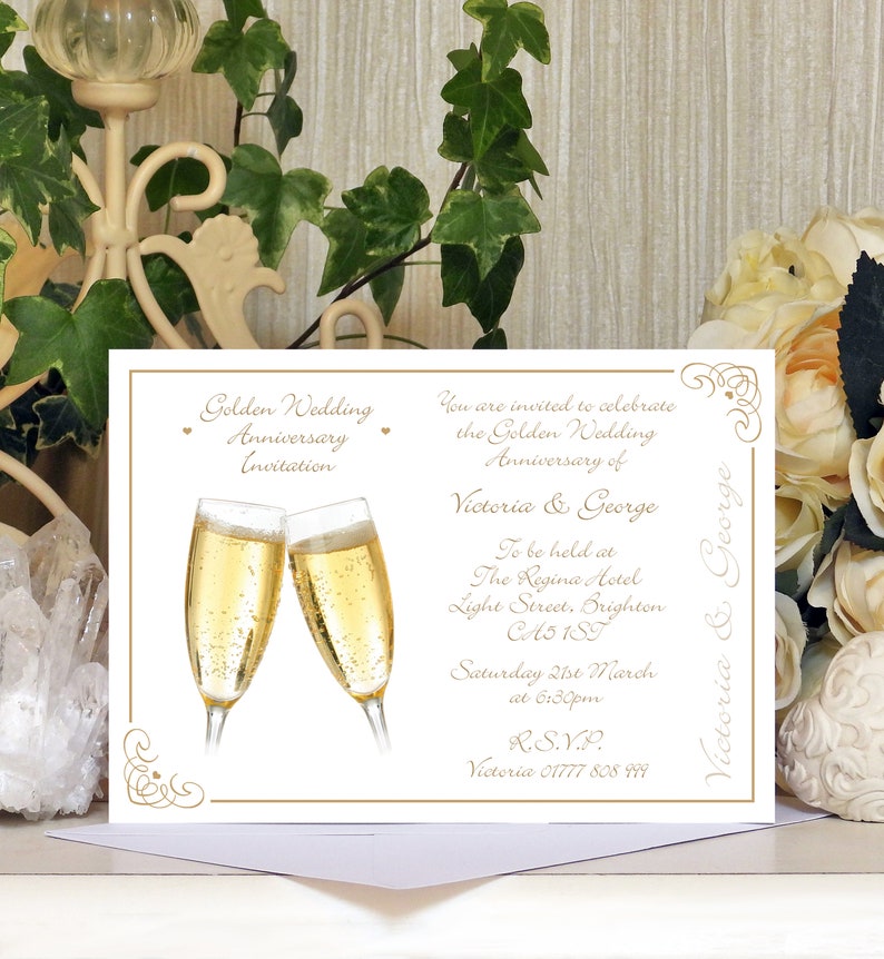 May include: A white invitation card with gold lettering announcing a Golden Wedding Anniversary celebration for Victoria and George. The invitation includes the date, time, and location of the event, as well as an RSVP contact number.