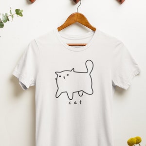 May include: White t-shirt with a simple black line drawing of a cat and the word "cat" underneath.