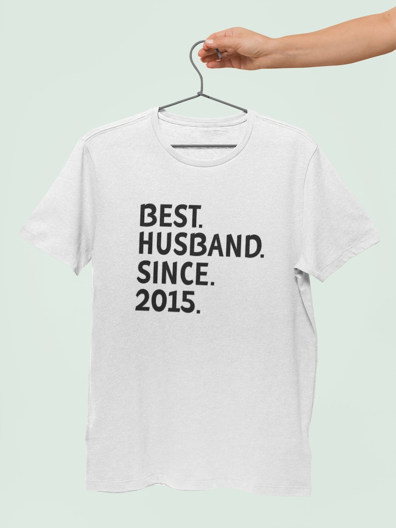 Op de afbeelding: Wit T-shirt met zwarte tekst die "BEST. HUSBAND. SINCE. 2015." luidt.