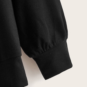 May include: Black long-sleeved sweatshirt with a ribbed cuff.