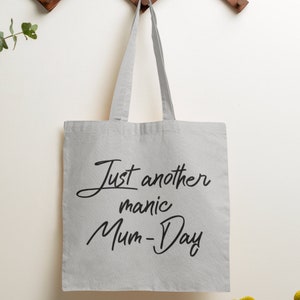 May include: A white canvas tote bag with black text that reads "Just another manic Mum-Day".