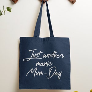 May include: A navy blue tote bag with white text that reads "Just another manic Mum-Day".