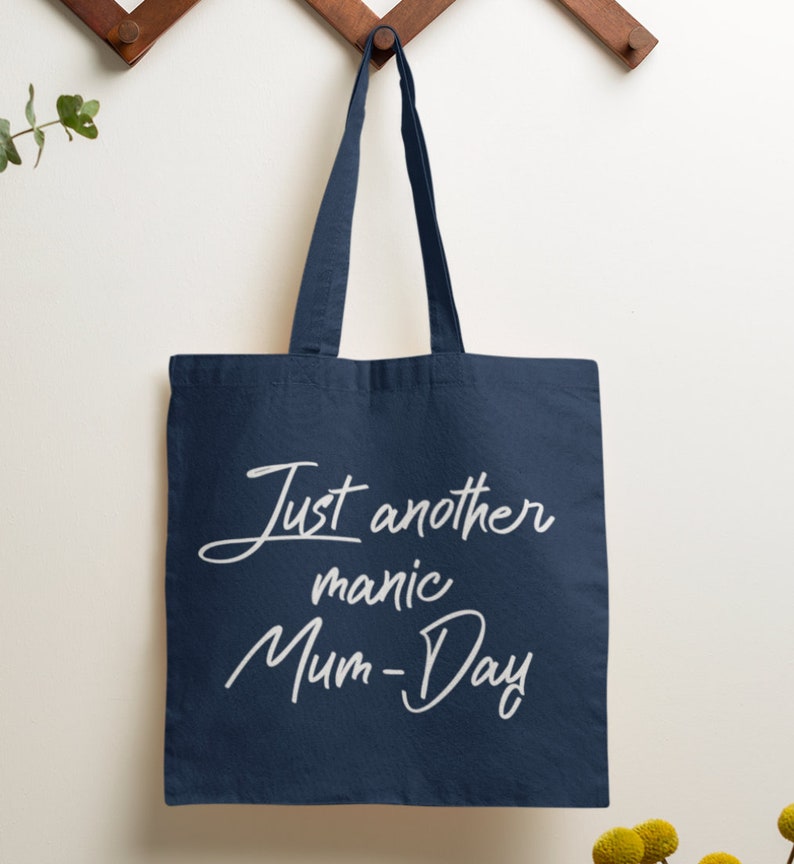 May include: A navy blue tote bag with white text that reads "Just another manic Mum-Day".