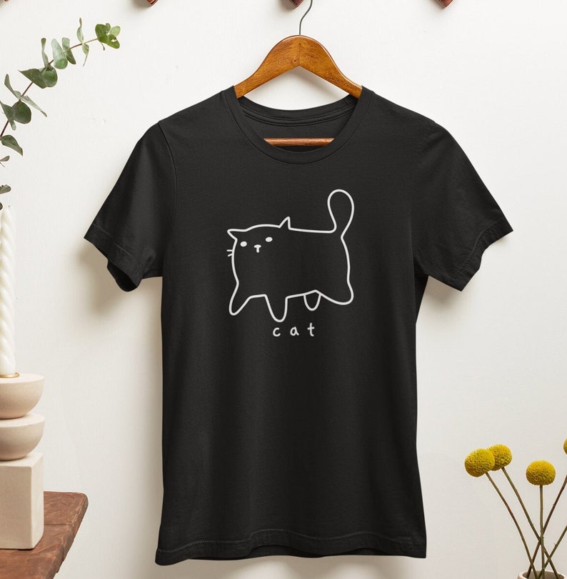 May include: Black t-shirt with a white outline of a cat and the word "cat" underneath.