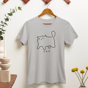 May include: A light gray t-shirt with a simple black line drawing of a cat and the word "cat" underneath.