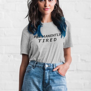 May include: A gray t-shirt with the text "PERMANENTLY TIRED" printed in black.