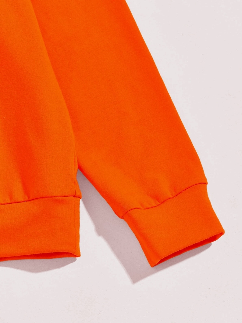 May include: Close-up of the orange fabric cuff of a long-sleeved sweatshirt.