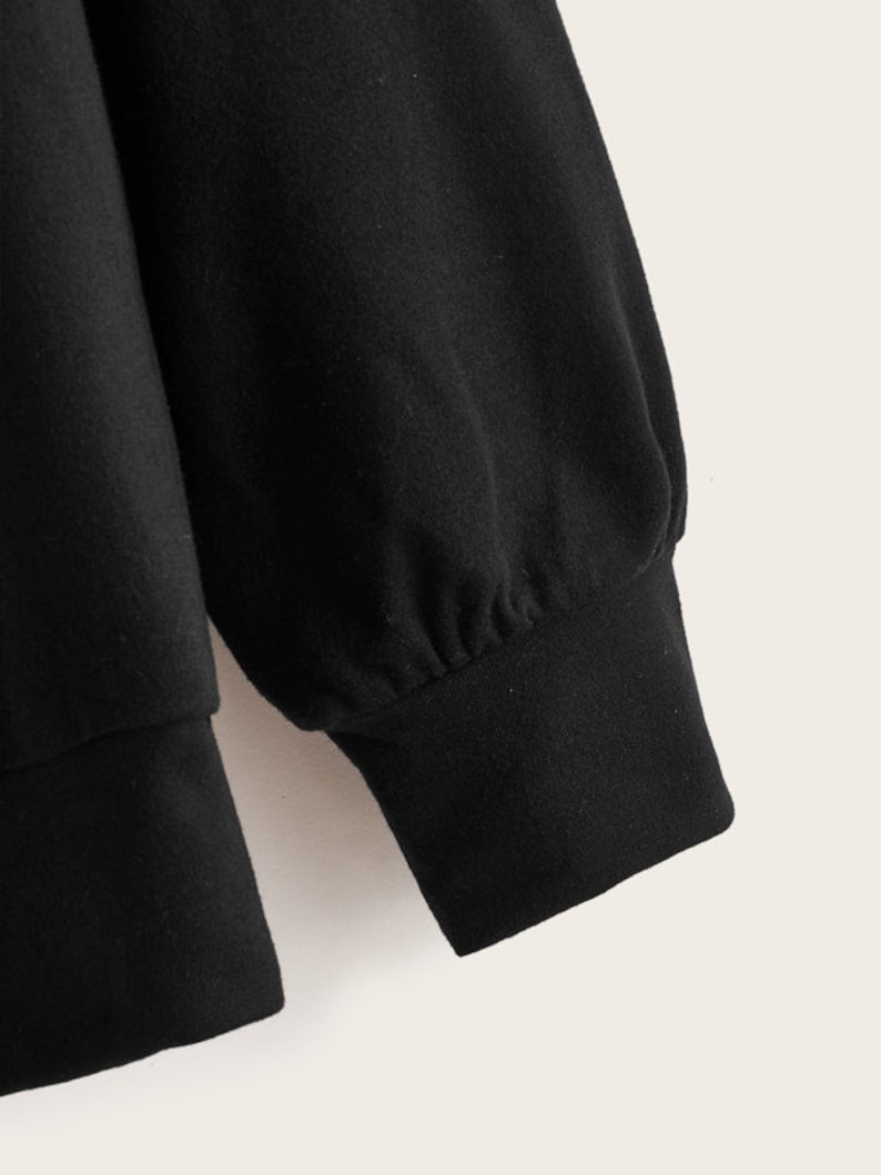 May include: Black long-sleeved sweatshirt with a ribbed cuff.