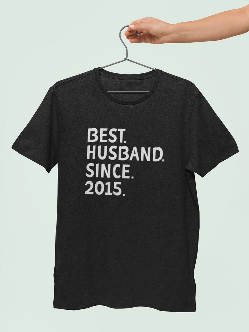 Op de afbeelding: Zwart T-shirt met witte tekst die "BEST. HUSBAND. SINCE. 2015." luidt.