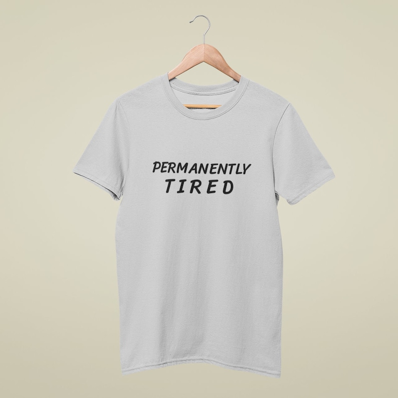 May include: A light gray t-shirt with the text "PERMANENTLY TIRED" printed in black.