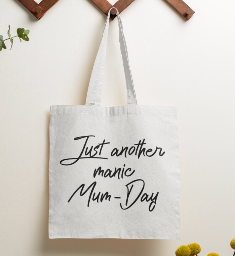 May include: White canvas tote bag with black text that reads "Just another manic Mum-Day".