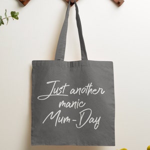 May include: A gray canvas tote bag with white text that reads "Just another manic Mum-Day".