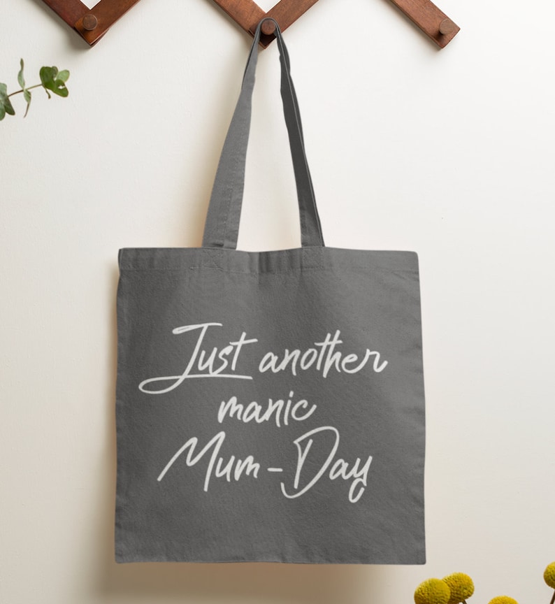 May include: A gray canvas tote bag with white text that reads "Just another manic Mum-Day".