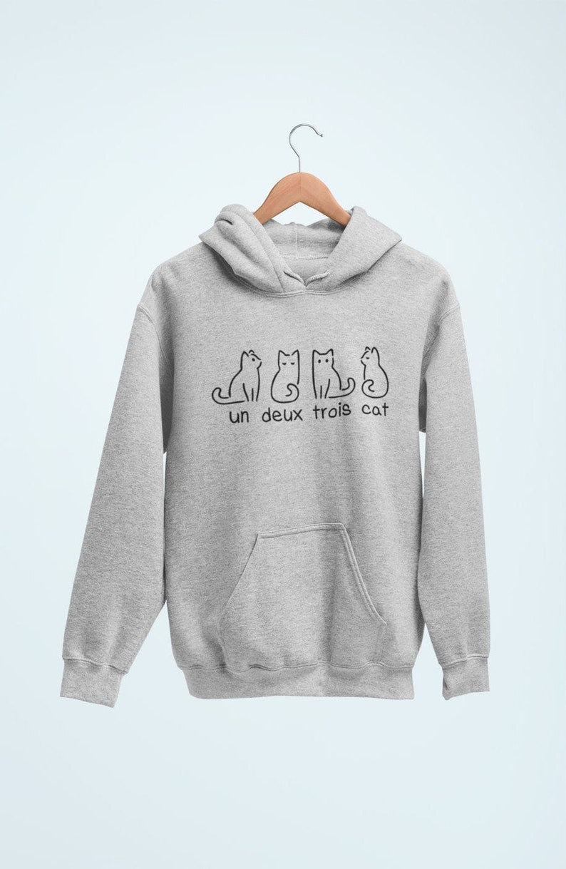 Op de afbeelding: Een grijs hoodie met een afbeelding van vier katten en de tekst "un deux trois cat".