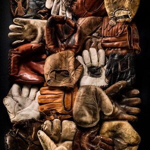 May include: A collection of vintage baseball gloves and mitts in various shades of brown, tan, and black leather. Some gloves have stitching details and are worn with age.