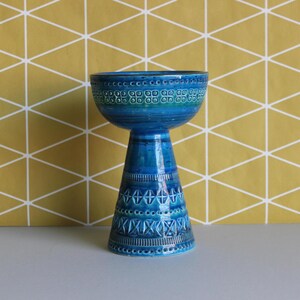 May include: A blue and green ceramic vase with a geometric pattern. The vase has a wide, bowl-shaped top and a tall, conical base.