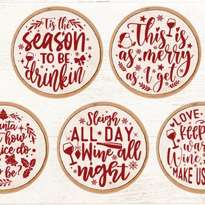 May include: Set of six round wooden signs with red text and images. The signs feature Christmas-themed sayings about wine, such as "Tis the season to be drinkin'" and "Sleigh all day, wine all night".